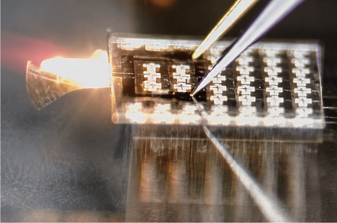 Optical micrograph of a thermal actuator glowing from Joule heating well above its safe operating power, showing irreversible high-power damage